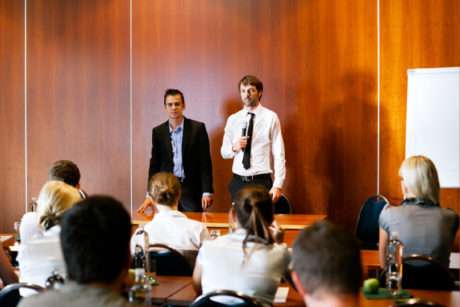 Two men presenting to an audience in a conference room.