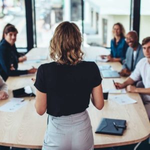 Businesswoman addressing a meeting in office with the leaders and other memebers