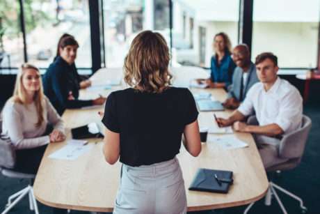Businesswoman addressing a meeting in office with the leaders and other memebers