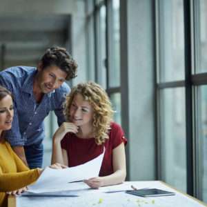 Group of colleagues discussing project in infomal meeting at office workstation