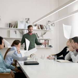 Unsatisfied manager throwing documents with the results of his employees while they're looking in shock.