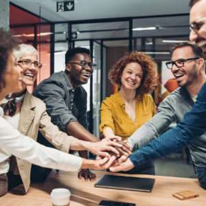 Smiling business persons stacking hands over the table