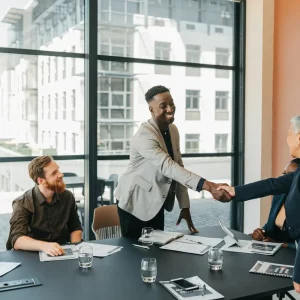 Diverse business professionals shaking hands in a modern conference room meeting.