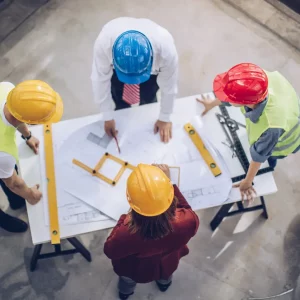 Overhead view of construction engineers reviewing blueprints on a job site.