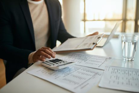 Close up of African American entrepreneur going through business budget and using calculator in the office