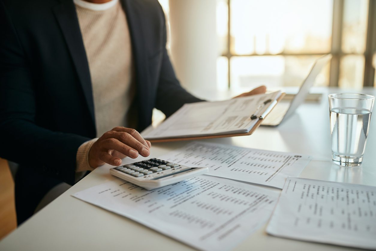 Close up of African American entrepreneur going through business budget and using calculator in the office