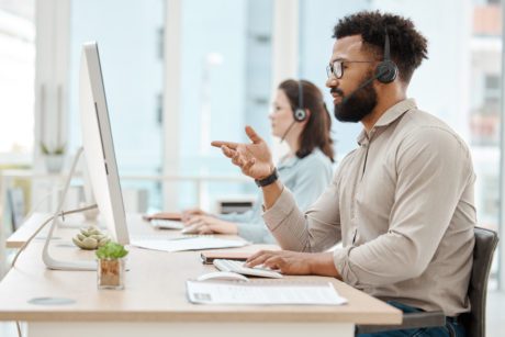Black man, customer support service office and working for online call center internet telemarketing business. Crm consultant at desk, helping client and consulting computer ai software for solution