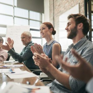 Shot of a team of businesspeople clapping hands while having a meeting in an office