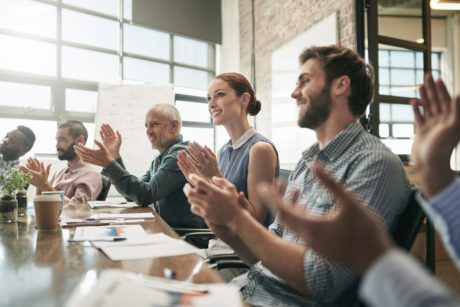 Shot of a team of businesspeople clapping hands while having a meeting in an office
