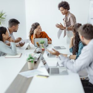 Upset Businesswoman Sitting With Aggressive Colleague In Meeting