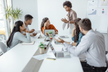 Upset Businesswoman Sitting With Aggressive Colleague In Meeting