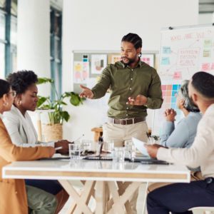 Business, black man or presentation with team, corporate training or conversation for sales growth or planning. African American male leader, employee or teamwork for charts, manager or collaboration