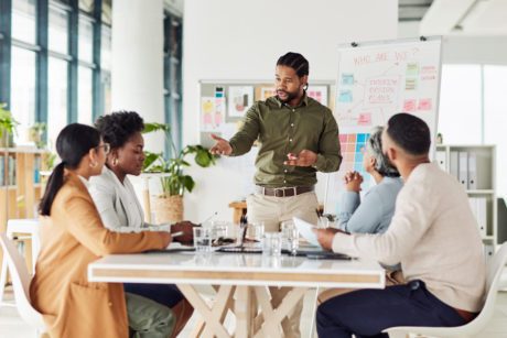 Business, black man or presentation with team, corporate training or conversation for sales growth or planning. African American male leader, employee or teamwork for charts, manager or collaboration