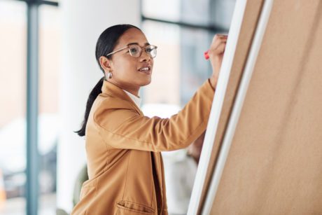 Creative woman, meeting and writing on Flipchart for team building, coaching or activity ideas at office.