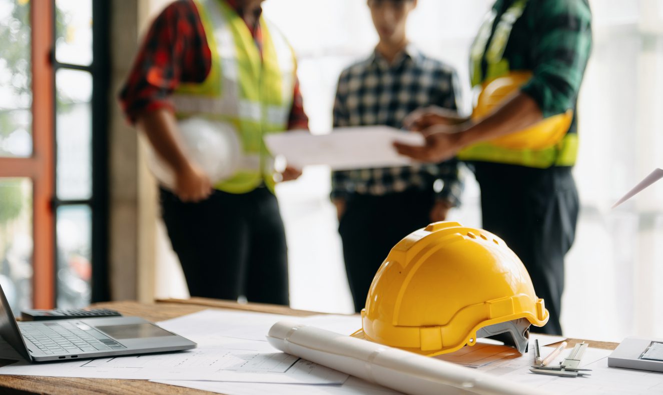 Engineer teams meeting working together wear worker helmets hardhat on construction site in modern city.Asian industry professional team in sun light