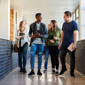 Group of young students walking down a hallway together at university