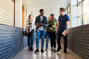 Group of young students walking down a hallway together at university